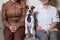 A cute dog Jack Russell Terrier is wearing a tie and sitting with two women on the couch