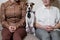 A cute dog Jack Russell Terrier is wearing a tie and sitting with two women on the couch