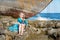 Cute doll girl sitting on the rocky shore of the sea ocean in azure celestial dress near an abandoned boat