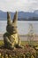 Cute Easter bunny from straw sits in a flowerbed