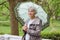 Cute elderly woman senior with an umbrella on the verandah in the park