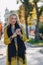 Cute emotional attractive blonde woman in coat with smartphone walks the city street. communication during the walk, lifestyle,