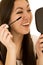 Cute ethnic teen applying her mascara holding a mirror laughing