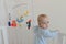 Cute European baby stands in a white canopy bed and turns to the camera.