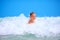 Cute excited boy having fun in waves, summer vacation