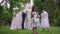 Cute excited Middle Eastern flower girl throwing roses petals smiling with blurred happy loving interracial couple at