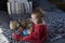 Cute fair baby girl sitting on bed playing with large blue rubber duck and vintage teddy bear