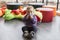 Cute fair baby girl sitting on floor in playroom sucking on toy pensively