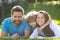 Cute family portrait hugging and embracing. Family lying on grass in park. Parents and children on vacation playing