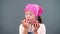 Cute farmer girl holding in hands two large ripe red apples, eats, bites them on a gray background in the studio