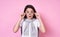 Cute fashionable emotional girl with glasses in a basic T-shirt on a pink background