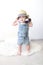 Cute fashionably dressed 10 months baby girl with suitcase at ho