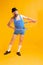 Cute fat young man wearing retro striped swimsuit and vintage bowler hat doing sport exercises isolated on bright yellow