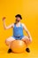 Cute fat young man wearing retro striped swimsuit and vintage bowler hat with huge ball isolated on bright yellow