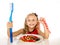 Cute female child eating dish full of sweets and holding huge toothbrush in dental care and health concept