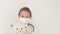 A cute female doctor in a medical mask hugs a polar teddy bear