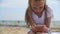 Cute focused girl using smartphone on beach at summertime