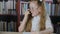 Cute focused schoolgirl in glasses writing and talking in classroom