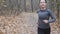 Cute focused woman jogging in the autumn park before half marathon race. Running Concept