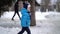 Cute four years old boy in blue winter clothes walks in snowy street