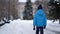 Cute four years old boy in blue winter clothes walks in snowy street