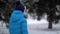 Cute four years old boy in blue winter clothes walks in snowy street