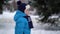 Cute four years old boy in blue winter clothes walks in snowy street