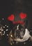 Cute French bulldog dog with headband of hearts lying on the floor with lights on a dark background. Vertical picture