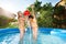 Cute friends pouring water over themselves in pool