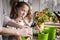 A cute funny girl transplants house plants with her mother. Houseplant care