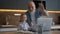 Cute and funny grandfather and grandson sitting at table with laptop look at camera, smile and wave to operator. Hand