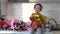 Cute funny little girl holding golden ballon 8 eight sitting on kitchen table with bouquets of spring flowers , greeting mother or