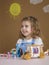 Cute funny preschooler little girl playing with construction toy blocks building a tower in kindergarten room