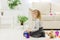 Cute funny preschooler little girl playing with construction toy blocks building a tower in a sunny room.