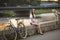 Cute girl with a bicycle and a dog sitting on the promenade in the soft sunset light.