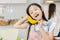 Cute girl child enjoy funny candid moment playing with banana at home kitchen