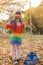 Cute girl cleaning fallen leaves with rake, outdoors.