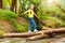 Cute girl crossing the river in summer forest