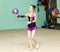 Cute girl doing crafty trick with ball on art gymnastics perform