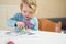 Cute girl drawing a fish using glass colors at home.