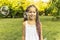 cute girl in dress and with African pigtails is standing in park against background of soap bubbles. Catching soap