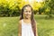 cute girl in dress and with African pigtails is standing in park against background of soap bubbles. Catching soap