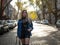 Cute girl with flowing hair in a denim jacket standing on the street with parked cars