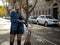 Cute girl with flowing hair in a denim jacket standing on the street with parked cars