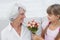 Cute girl giving a bunch of flowers to her grandmother