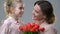 Cute girl giving flowers to beloved mother, surprise for birthday or March 8