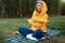 cute girl with glasses in an orange hoodie is sitting in a park in nature expressing kind emotions