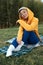 cute girl with glasses in an orange hoodie is sitting in a park in nature expressing kind emotions