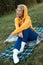 cute girl with glasses in an orange hoodie is sitting in a park in nature expressing kind emotions