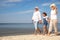 Cute girl with grandparents spending time together on sea beach